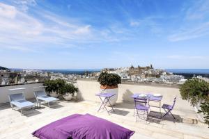 eine Terrasse mit Tischen und Stühlen und Stadtblick in der Unterkunft Bartago Luxury House in Ostuni