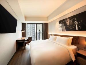 a hotel room with a bed and a desk and a window at Mercure Ambassador Seoul Hongdae in Seoul