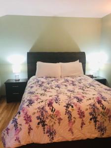 a bedroom with a bed with a floral comforter and two lamps at Midnight Sun Vacation Home in Whitehorse