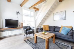 a living room with a couch and a tv at Herenweg Apartments in Hollum