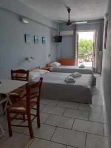 a bedroom with two beds and a table and chairs at Almiriki Rooms in Agios Kirykos