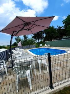 a pink umbrella and chairs and a swimming pool at House Mirjana in Smoljanac