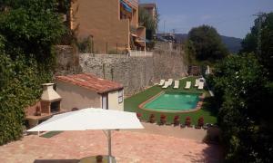 a house with a swimming pool and an umbrella at Allotjaments Rurals Can Pere Petit in Santa Pau