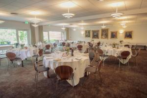 a banquet room with tables and chairs with white tablecloths at Fjelsted Skov Hotel & Konference in Ejby