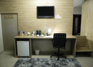 a desk with a chair and a television on a wall at Tezla Hotel in Primavera do Leste