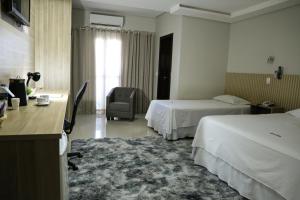 a hotel room with two beds and a desk at Tezla Hotel in Primavera do Leste