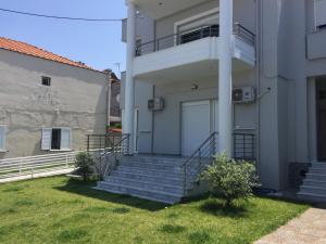 a white house with stairs and a grass yard at Olea Garden Apartments in Stavros