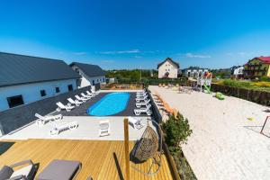 a swimming pool with lounge chairs and a deck with a swimming pool at Domki Borys in Jastrzębia Góra