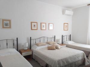 2 Betten in einem Schlafzimmer mit weißen Wänden in der Unterkunft LOCANDA Roma sleep & food in Donoratico