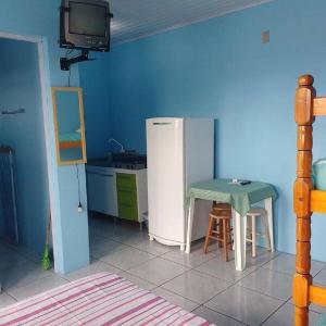 a kitchen with a small table and a refrigerator at Residencial Água Azul in Capão da Canoa