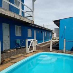 a swimming pool in front of a blue building at Residencial Água Azul in Capão da Canoa