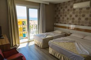 a hotel room with two beds and a large window at Acem Hotel in Ayvalık
