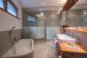 a bathroom with a tub and a sink and a shower at Europe Hotel & Spa in Zermatt