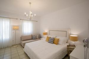 a white bedroom with a large bed and a couch at Eutuxia Rooms & Studios in Apollonia