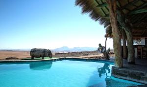 Un éléphant se tient à côté d'une piscine dans l'établissement Rostock Ritz Desert Lodge, à Cha-re