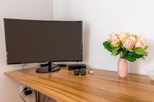 a computer monitor and a vase of pink roses on a desk at Pensiunea Armonia in Nădăşelu