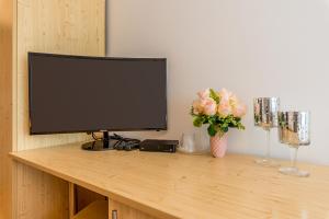 a television sitting on top of a wooden table with flowers at Pensiunea Armonia in Nădăşelu