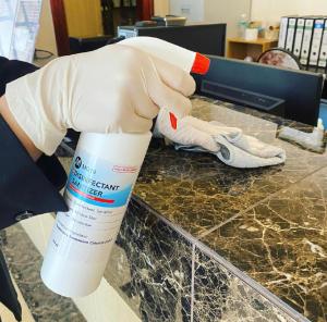 a person wearing gloves holding a bottle of bleach on a counter at Hotel Venice in Kuala Lumpur