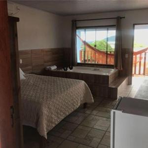 1 dormitorio con cama, bañera y ventana en Pousada Estrela Guia, en Pirenópolis