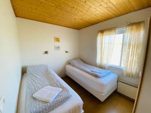 two beds in a small room with a window at Ábót - Riverside Cottage in Egilsstadir