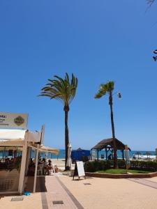 deux palmiers sur une plage avec un ciel bleu dans l'établissement APARTAMENTO RONDA 4 BOLICHES Primera línea de playa, à Fuengirola