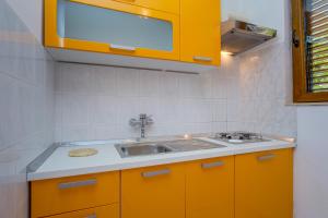 a kitchen with yellow cabinets and a sink at Apartments Villa Julija in Mali Lošinj