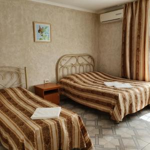 アゴイにあるGuest House Solnechnaya dacha 2のベッド2台とテーブルが備わるホテルルームです。