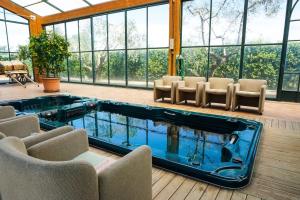a swimming pool with chairs and a room with windows at Pian De' Somari in Pitigliano