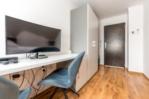 a desk with a monitor and a blue chair at Pensiunea Armonia in Nădăşelu