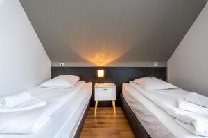 two beds in a small room with a night stand at Pensiunea Armonia in Nădăşelu