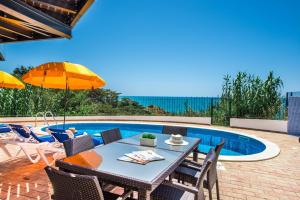 a patio with a table and chairs next to a swimming pool at Forte São João Villas da Praia in Albufeira