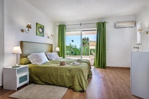 a bedroom with a large bed with green curtains at Forte São João Villas da Praia in Albufeira