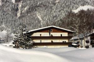 ein Gebäude im Schnee vor einem Berg in der Unterkunft Tirolerhaus in Walchsee