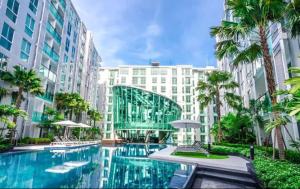 a large swimming pool with palm trees and buildings at City Center Residence in Pattaya