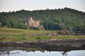 un castello in cima a una collina vicino a un corpo d'acqua di The Tables Guest House a Dunvegan