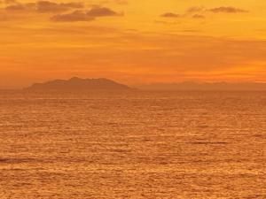 a sunset over the ocean with mountains in the background at Cala Dei Mori in Livorno