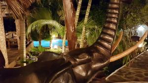 una estatua de un animal con colmillos delante de una piscina en Boutique Hotel Nyumbani Tembo, en Watamu