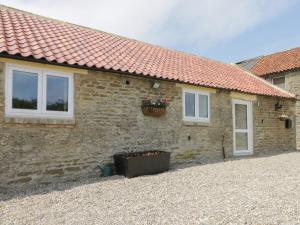 a stone house with a flower pot on the side of it at Crabtree Cottage in Scarborough