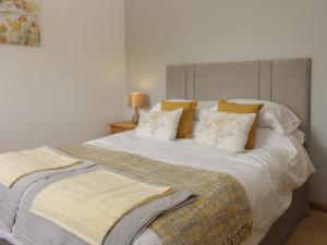 een groot bed met witte lakens en gele kussens bij Crabtree Cottage in Scarborough