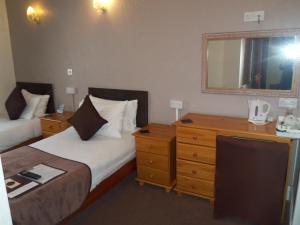 a hotel room with two beds and a dresser and a mirror at Novello Blackpool in Blackpool