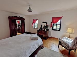 a bedroom with a bed and a chair and windows at The Spinner's Cottage in Donegal