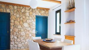 ein Esszimmer mit einer Steinmauer sowie einem Holztisch und Stühlen in der Unterkunft Welcomely - Sardinian Stone House in Torre Grande