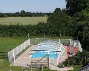 una valla alrededor de una piscina en un campo en Chambres d'Hôtes Les Piéris, en Grandcamp-Maisy
