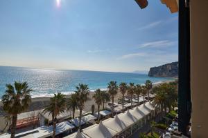 a view of a beach with palm trees and umbrellas at Hotel Garibaldi in Finale Ligure