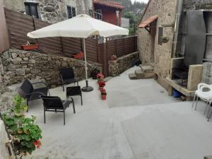 a patio with an umbrella and chairs and tables at Casa Rústica Pedroso in Padrón