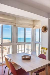 a dining room with a table and chairs and windows at Una ventana al mar in Rota