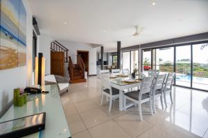 a dining room and living room with a table and chairs at Villa Elysian in Ban Bang Po