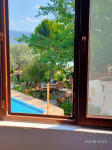 a window with a view of a garden with a pool at Selenes Pansiyon in Kapıkırı