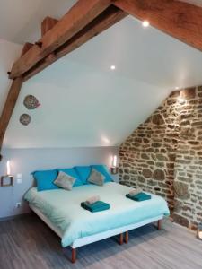 Bett in einem Zimmer mit einer Steinmauer in der Unterkunft Le Cottage de L Abbaye in Lonlay-lʼAbbaye