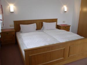 a large bed in a room with two night stands at Haus Waldfriede in Pertisau